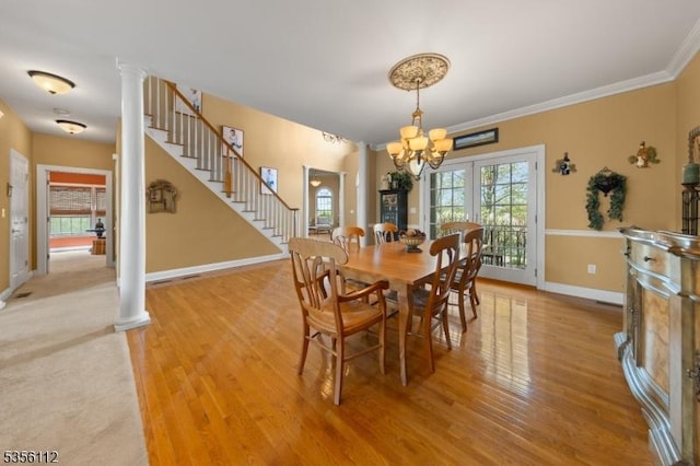 dining area with decorative columns, light wood finished floors, a chandelier, and ornamental molding