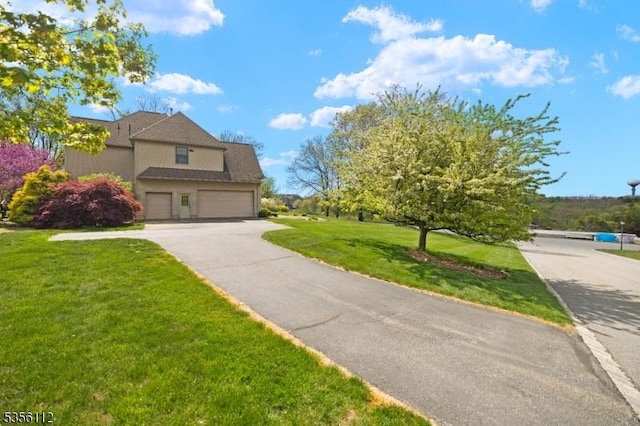 view of front of home featuring a front yard, an attached garage, and asphalt driveway