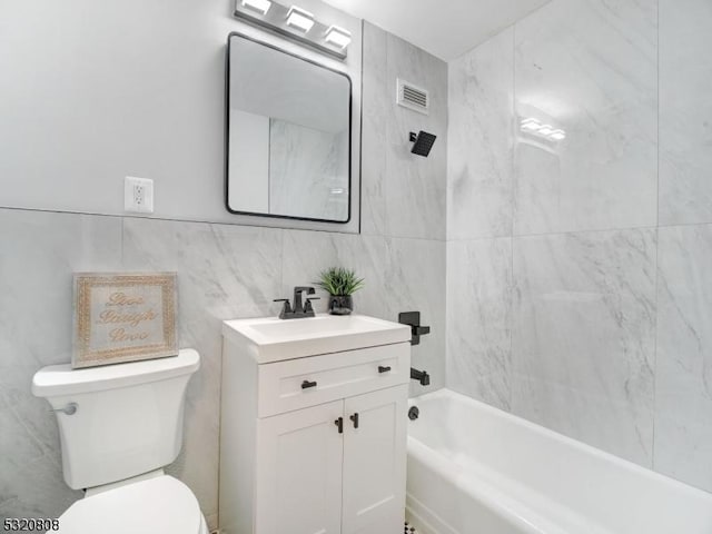 full bath with tile walls, toilet, vanity, and shower / bathtub combination