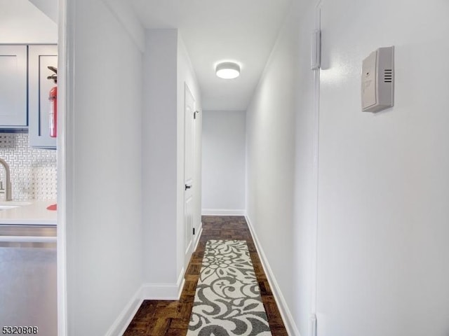 hall featuring baseboards and a sink