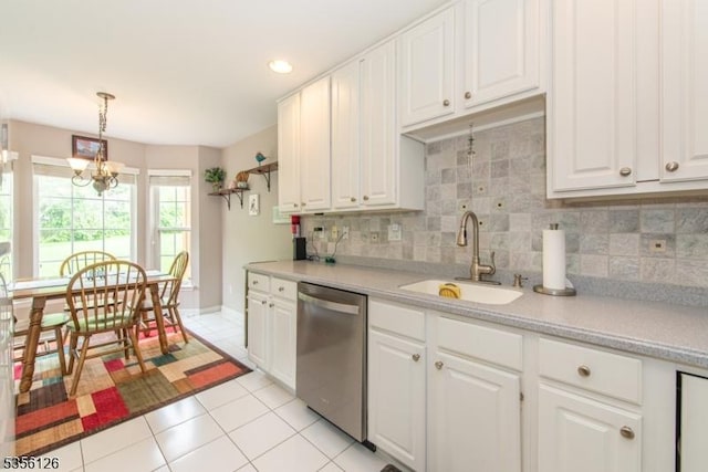 kitchen featuring stainless steel dishwasher, a sink, light tile patterned floors, light countertops, and white cabinets