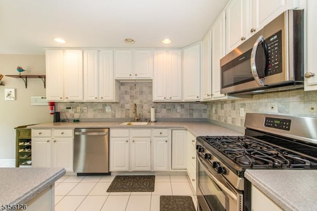 kitchen featuring stainless steel appliances, a sink, white cabinetry, backsplash, and recessed lighting