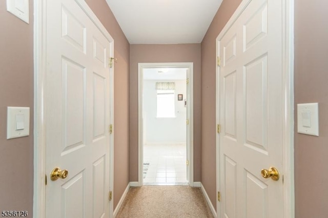 hall featuring baseboards and light carpet