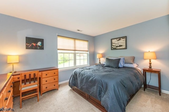 bedroom featuring light colored carpet, baseboards, and a desk