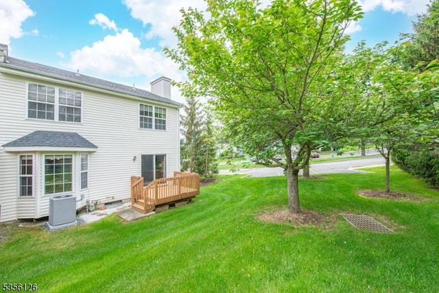 back of house featuring cooling unit, a deck, a lawn, and a chimney