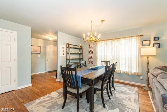 dining space with a chandelier, light wood-type flooring, and baseboards