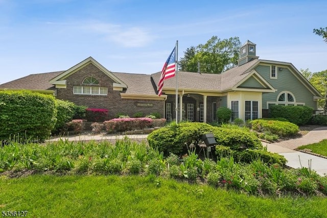 view of front facade with brick siding and a shingled roof
