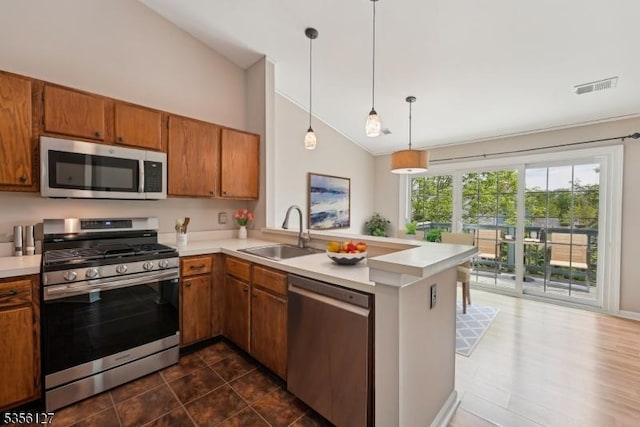 kitchen featuring lofted ceiling, visible vents, a sink, light countertops, and appliances with stainless steel finishes