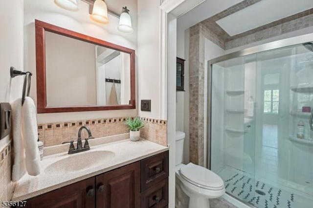 bathroom featuring a shower stall, backsplash, vanity, and toilet