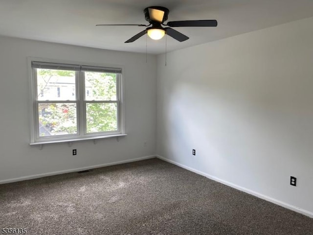 carpeted spare room featuring ceiling fan and baseboards