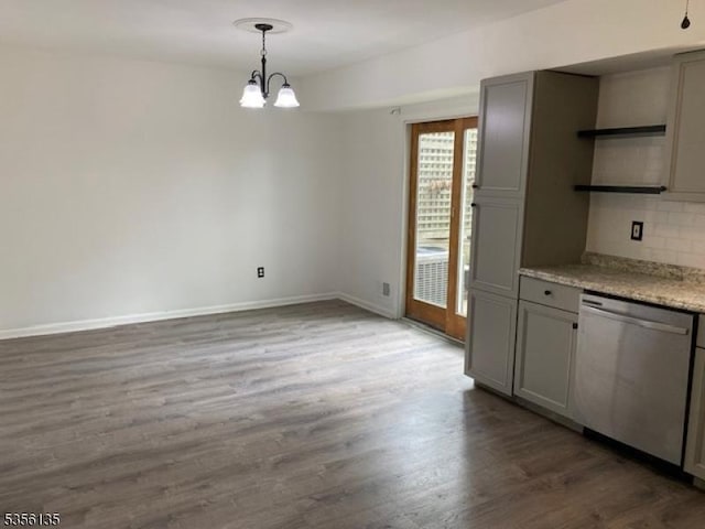 unfurnished dining area with dark wood-style flooring, a chandelier, and baseboards