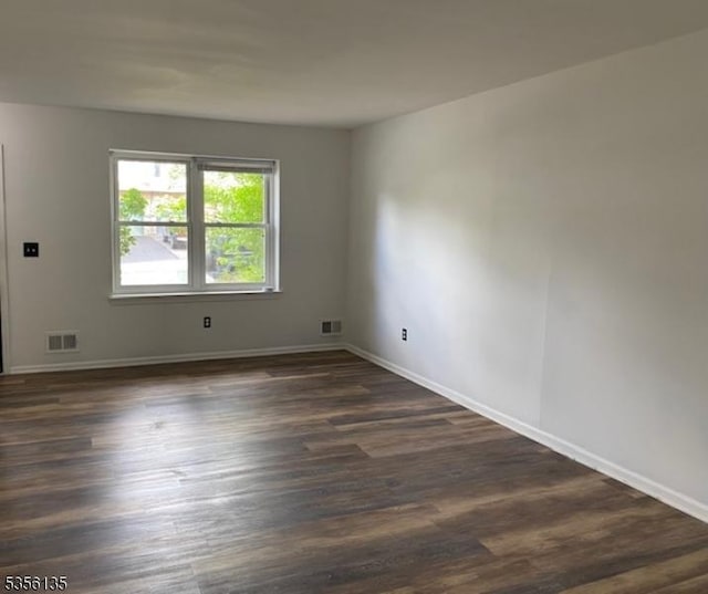 empty room featuring dark wood-type flooring and baseboards