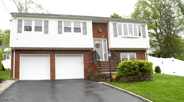bi-level home with brick siding, aphalt driveway, a garage, and fence