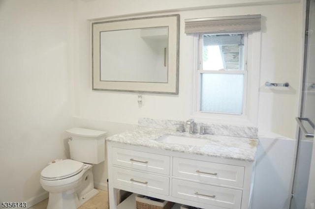 bathroom featuring toilet, a shower with shower door, and vanity