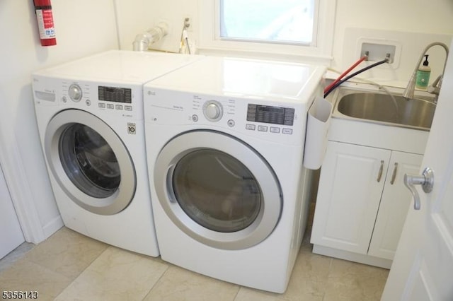 washroom with washer and dryer, cabinet space, and a sink