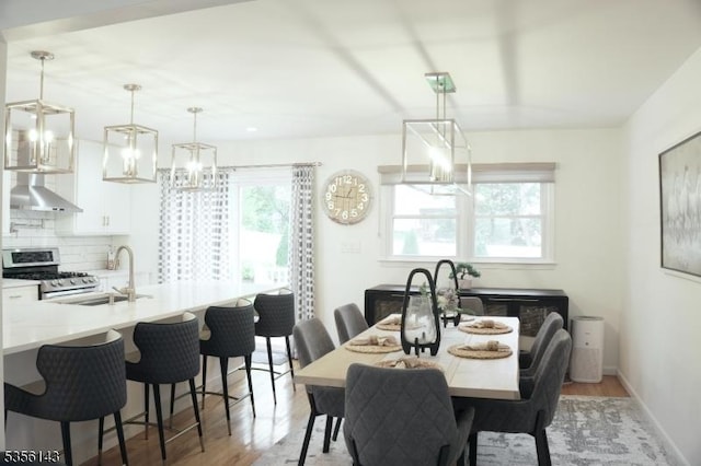 dining room featuring a chandelier, light wood-style flooring, and baseboards