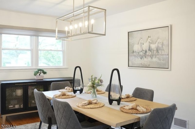 dining area featuring a notable chandelier, visible vents, and wood finished floors