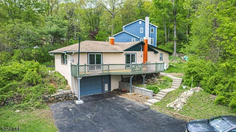 2 Ridge Rd E, Vernon Twp, NJ 07422 - view of front of home with asphalt driveway, a chimney, stucco siding, a wooden deck, and a garage