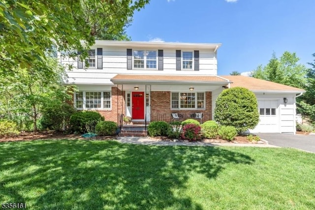 traditional-style house with a garage, driveway, a front lawn, and brick siding
