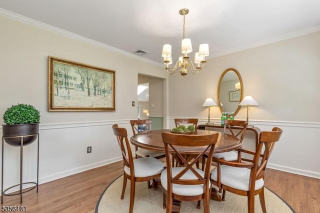 dining area with wood finished floors, crown molding, and a chandelier