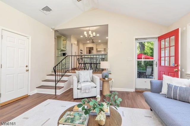 living area featuring vaulted ceiling, wood finished floors, a chandelier, stairs, and baseboards
