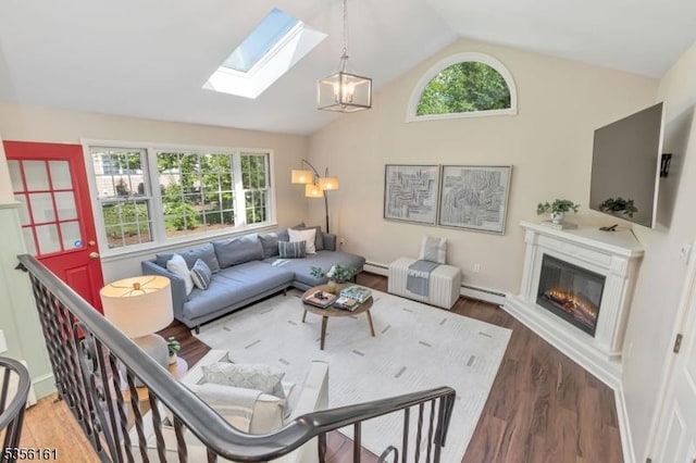 living area featuring a skylight, baseboard heating, lofted ceiling, plenty of natural light, and wood finished floors