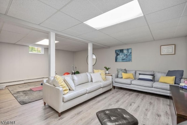 living area featuring a baseboard heating unit, wood finished floors, and a drop ceiling
