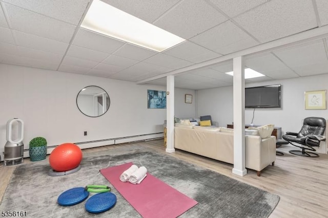 workout area with wood finished floors, a paneled ceiling, and baseboard heating