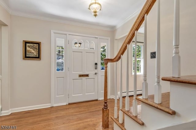 entryway with crown molding, a baseboard heating unit, light wood-style flooring, stairway, and baseboards