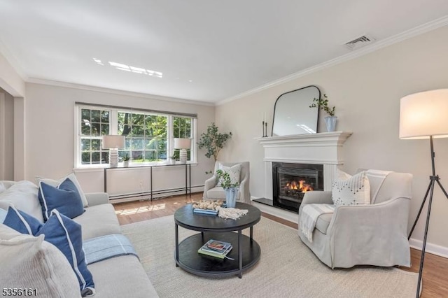 living room featuring a baseboard heating unit, wood finished floors, crown molding, a glass covered fireplace, and baseboards