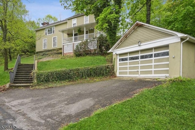 view of front facade featuring stairway, a chimney, a front yard, a garage, and stucco siding