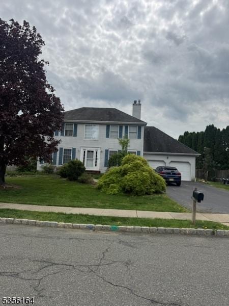 colonial inspired home featuring a chimney, aphalt driveway, and a front lawn