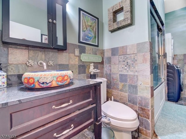 bathroom with tile walls, toilet, wainscoting, and vanity