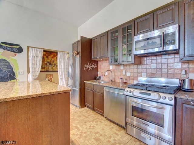 kitchen with backsplash, light floors, light stone counters, and appliances with stainless steel finishes