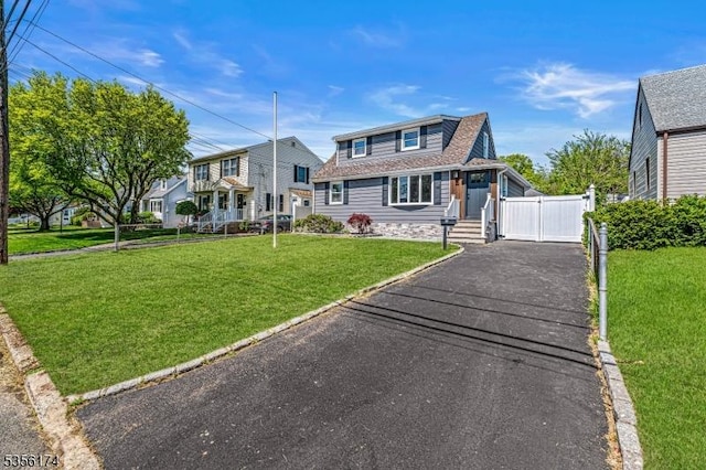 view of front of home with asphalt driveway, a front yard, a gate, and a shingled roof