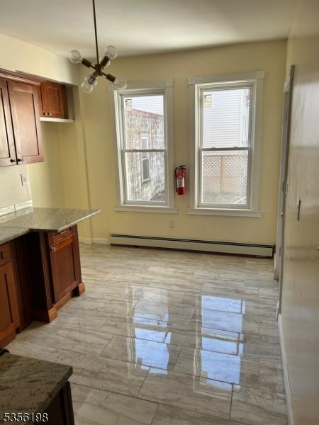 unfurnished dining area with a baseboard radiator, a chandelier, and baseboards