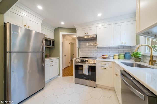 kitchen with appliances with stainless steel finishes, a sink, under cabinet range hood, light countertops, and recessed lighting