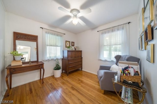 sitting room with light wood-type flooring, a ceiling fan, and baseboards