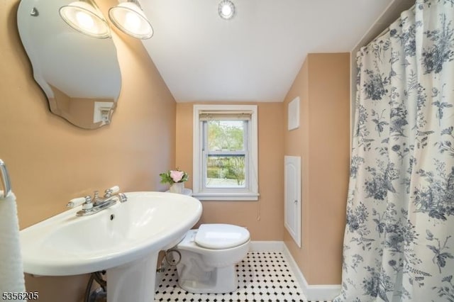 full bathroom featuring vaulted ceiling, baseboards, toilet, curtained shower, and tile patterned floors