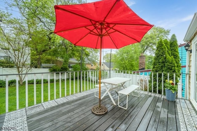 deck with outdoor dining area and a yard