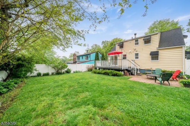 rear view of property featuring a wooden deck, a patio area, and a shingled roof