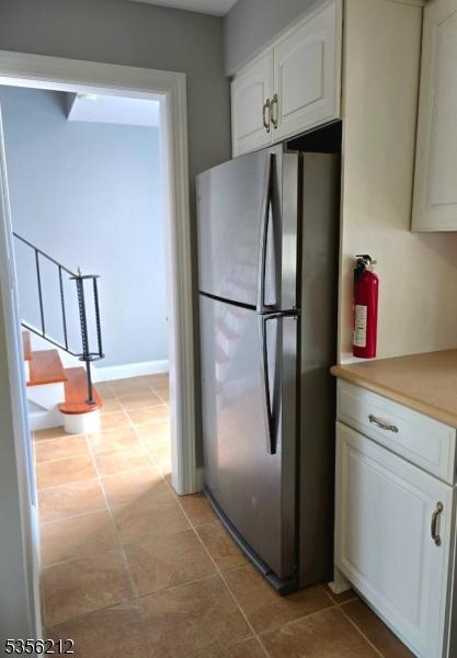 899 Robin Rd Unit 899, Hillsborough Twp, NJ 08844 - kitchen featuring freestanding refrigerator, white cabinets, light countertops, light tile patterned floors, and baseboards