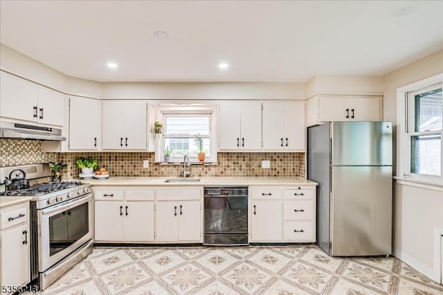 kitchen with stainless steel appliances, under cabinet range hood, a sink, and light countertops