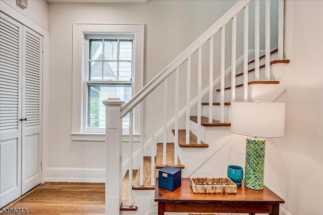 staircase featuring plenty of natural light, baseboards, and wood finished floors
