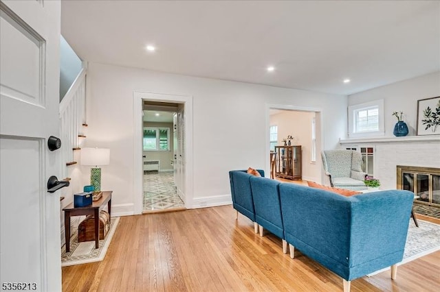 living area with light wood-style floors, radiator, a fireplace, recessed lighting, and baseboards