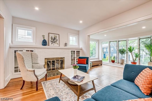 living room featuring a brick fireplace, light wood-type flooring, and recessed lighting