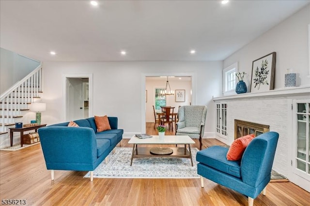 living room featuring stairs, healthy amount of natural light, wood finished floors, recessed lighting, and a brick fireplace