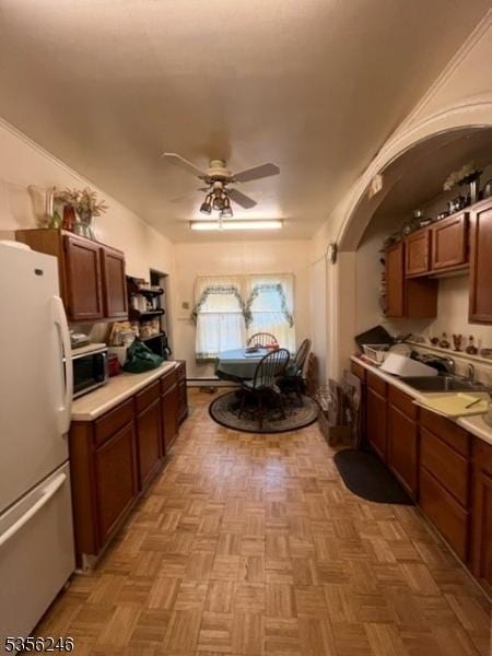 kitchen featuring freestanding refrigerator, stainless steel microwave, ceiling fan, and light countertops