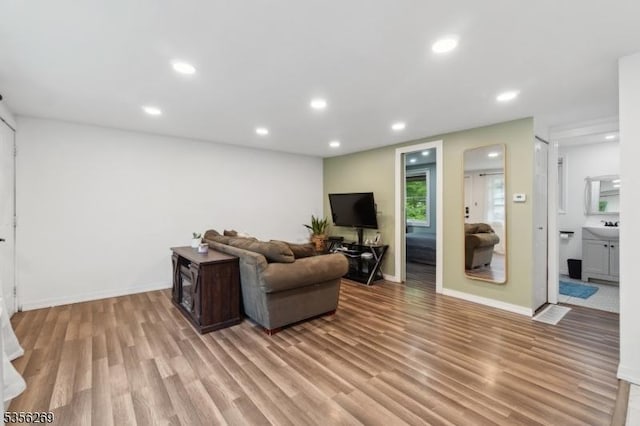 living area with light wood-style flooring, recessed lighting, and baseboards