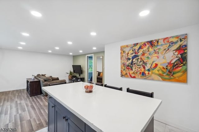 kitchen with light countertops, recessed lighting, a kitchen island, open floor plan, and light wood-style floors